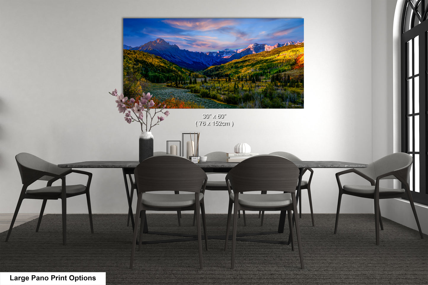 a dining room table with a painting of mountains in the background