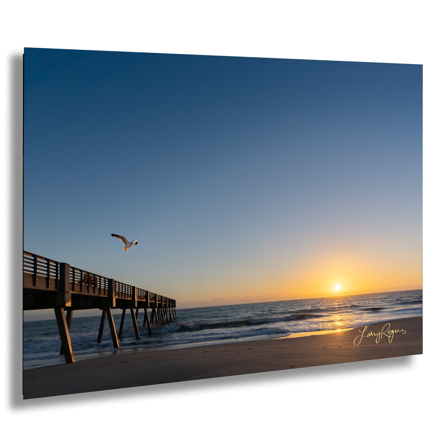 a bird flying over a pier at the beach