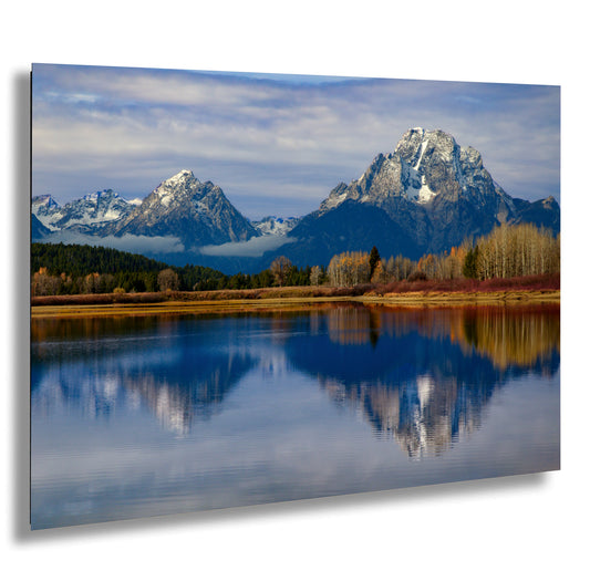 a mountain range is reflected in the still water of a lake