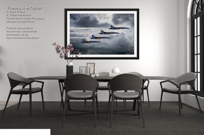 a dining room table with four chairs and a picture hanging on the wall