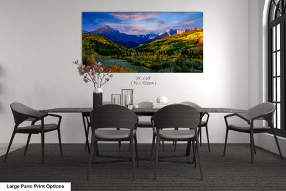 a dining room table with a painting of mountains in the background