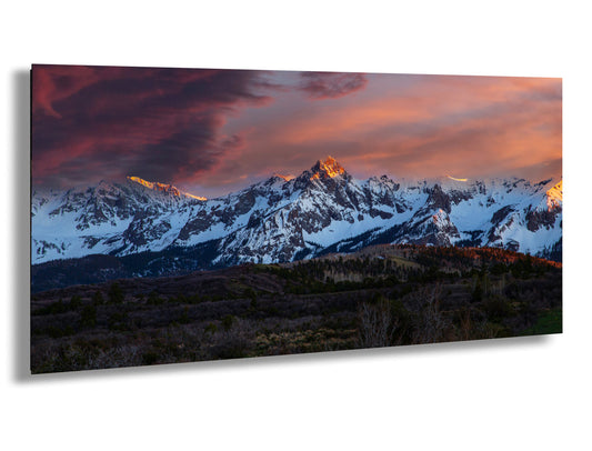 a snow covered mountain range under a cloudy sky