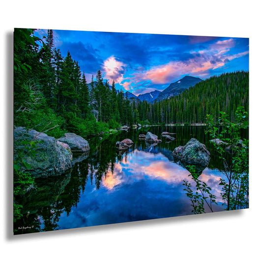 a lake surrounded by trees and rocks under a cloudy sky