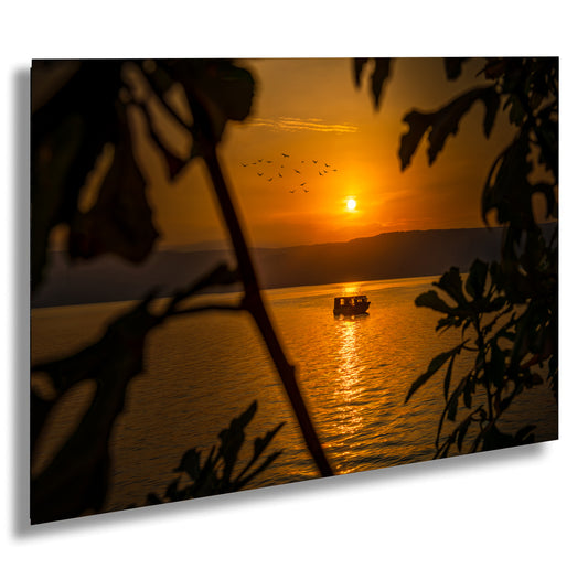 a boat floating on top of a body of water at sunset