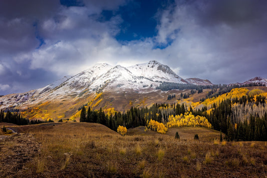 Beautiful snowy mountain peak with blue sky and clouds, with golden aspens below. Taken near Crested Butte Colorado