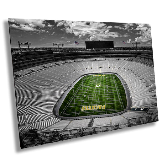 The empty stadium stands like a quiet sentinel, its vast rows of seats circling a lush green field marked with “Packers.” Overhead, soft clouds drift in a black-and-white sky, framing the silence before the roar of the game.